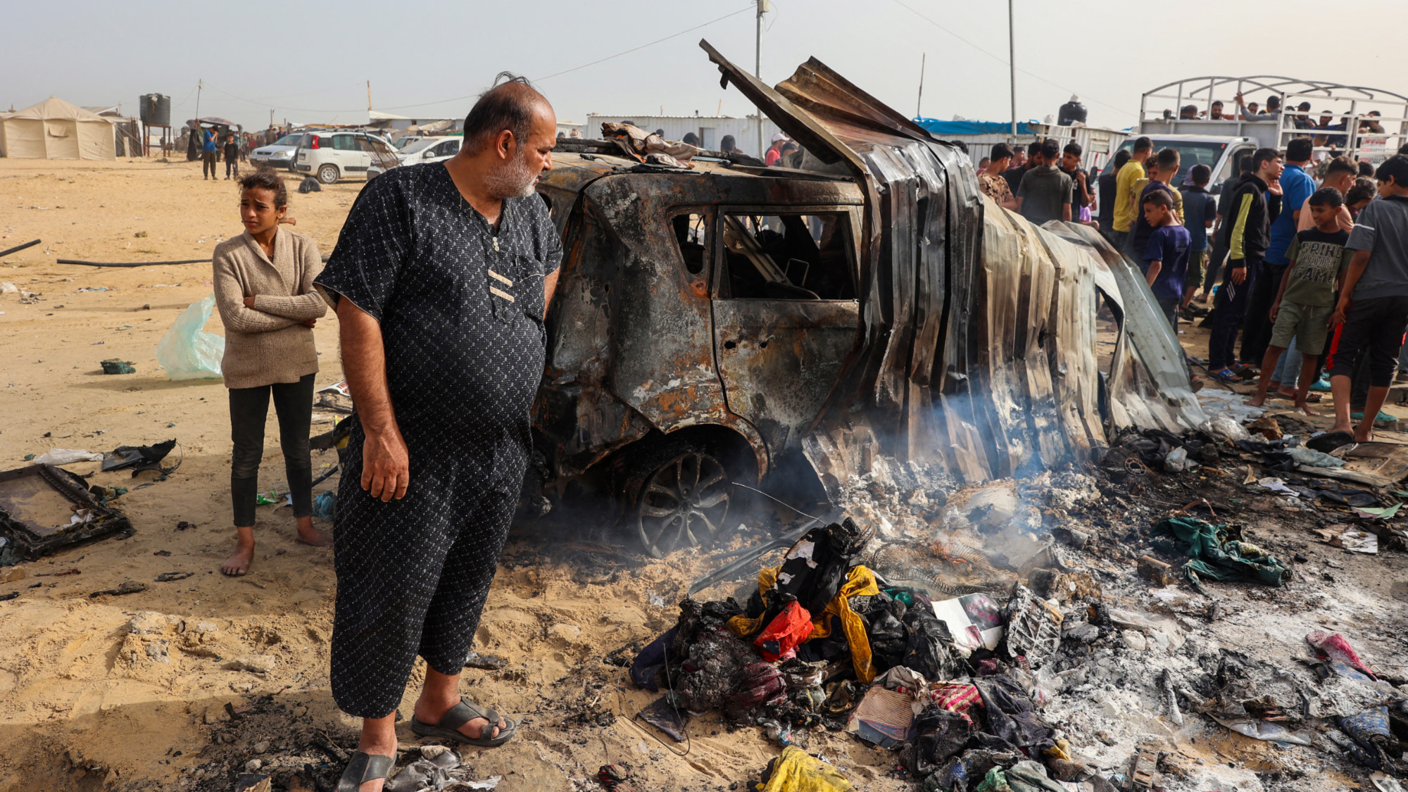 فلسطينيون يتجمعون في موقع غارة إسرائيلية على منطقة مخيم للنازحين في رفح في 27 مايو 2024 (Eyad Baba/AFP)